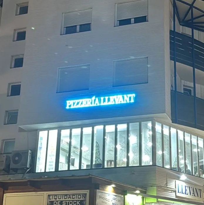 Rótulo de neón LED azul de la Pizzería Llevant en un edificio de Peñíscola